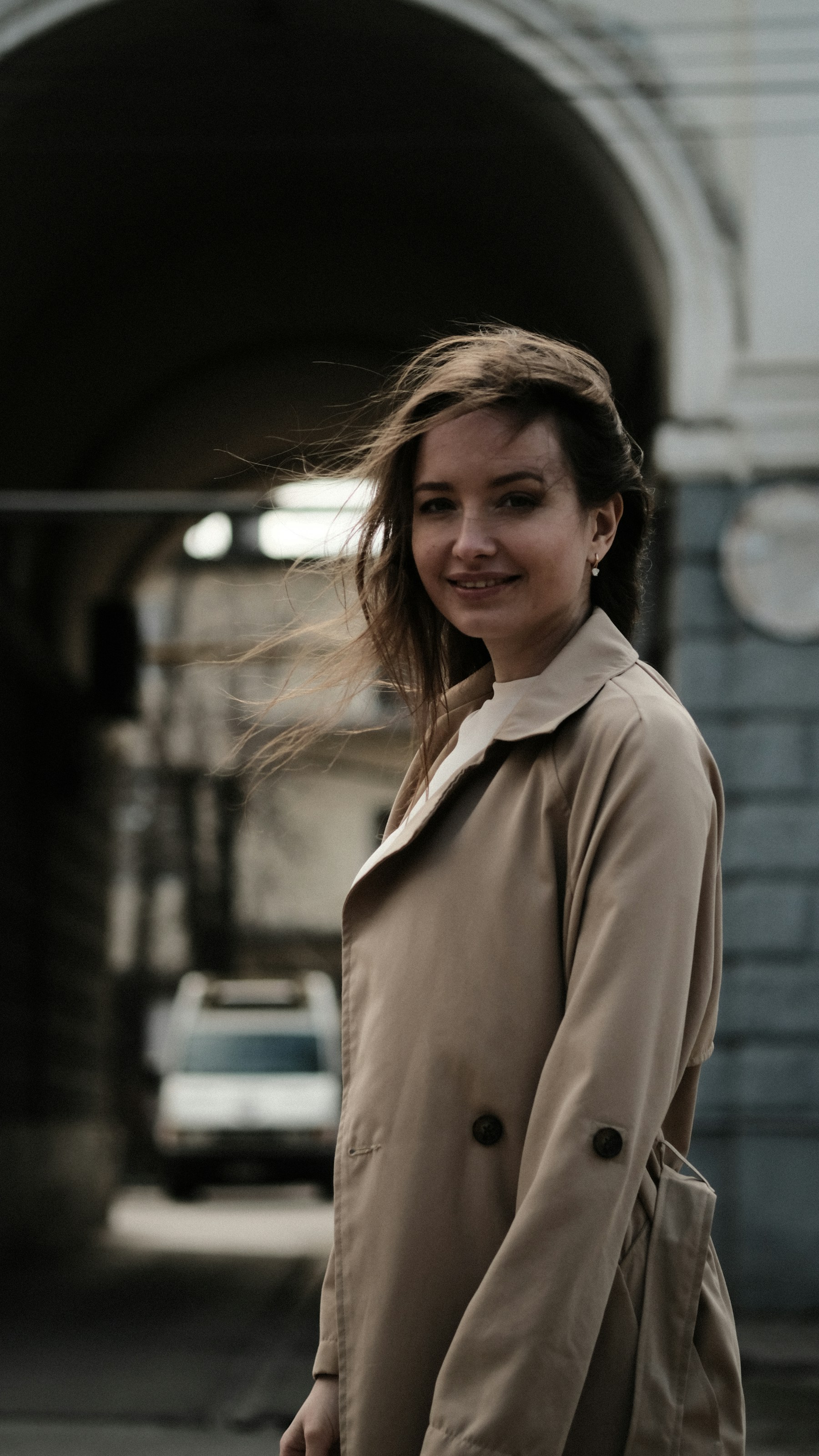 a woman in a trench coat is walking down the street