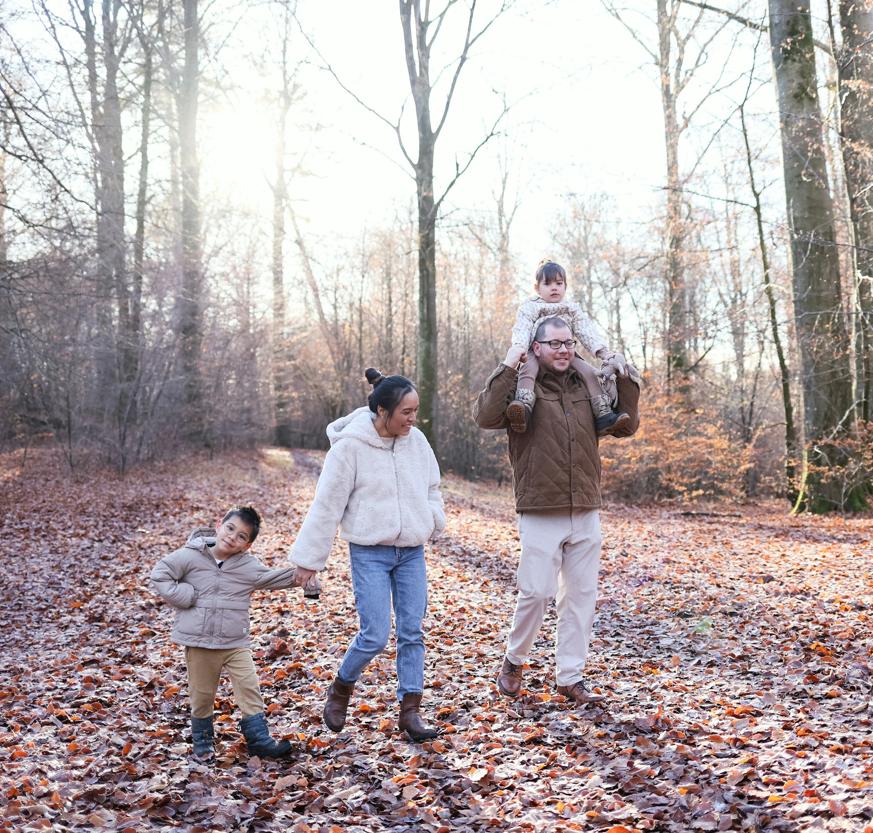 Family walking on a path covered with autumn leaves