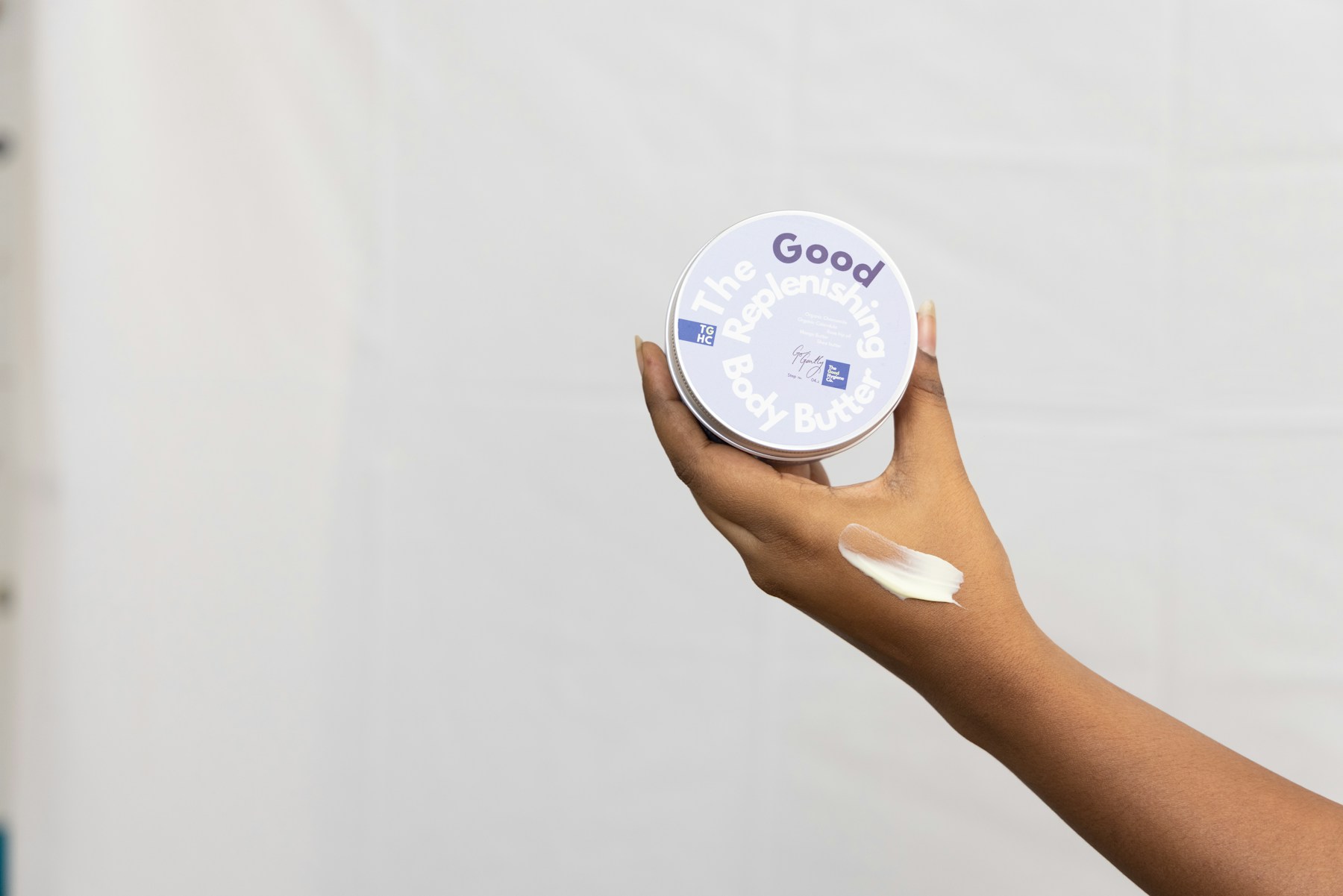 Hand holding a jar with cream and smeared on skin