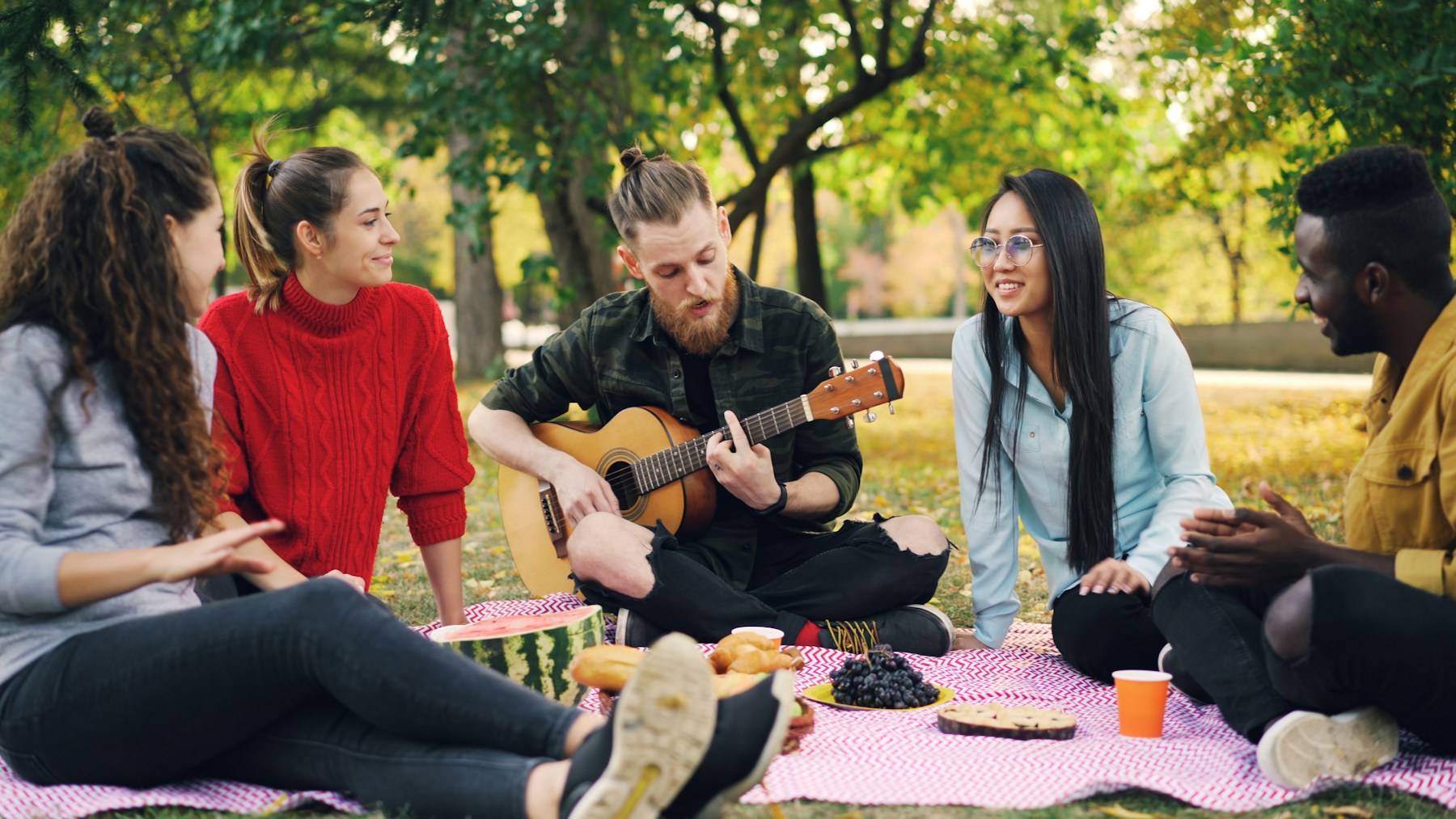 Friends enjoy a picnic with music in the park